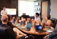 man standing in front of people sitting beside table with laptop computers