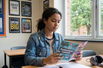 Jeune fille réfléchie avec brochure sur carrières audiovisuelles